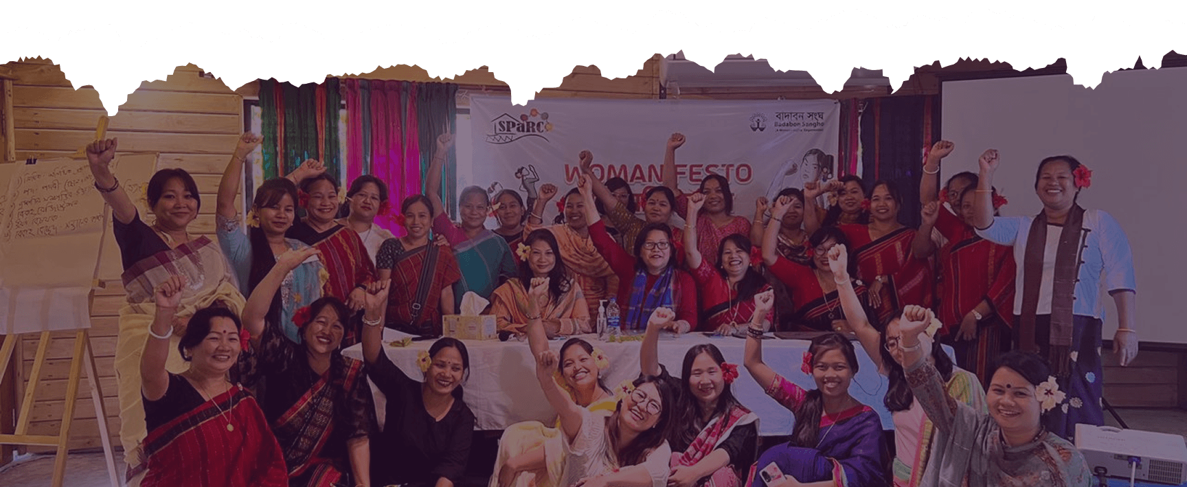 Participants at a SPaRC Womanifesto gathering raising their hands together.