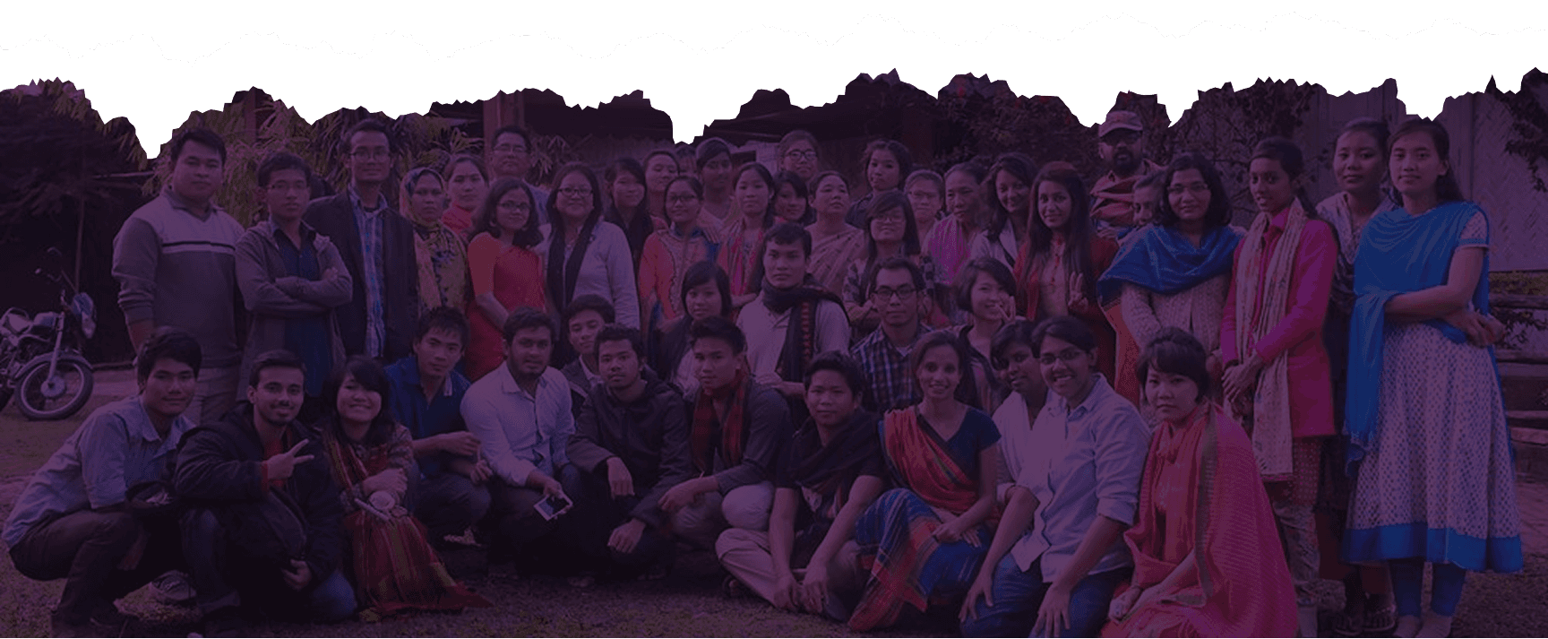 A large group of young interns and staff seated and standing together for a group photograph.